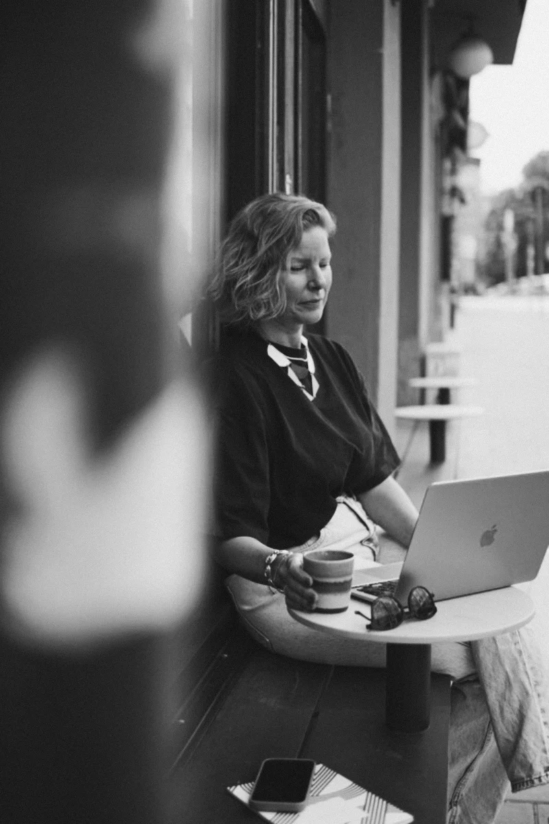 Sara arbetar vid sin laptop med en kopp kaffe.