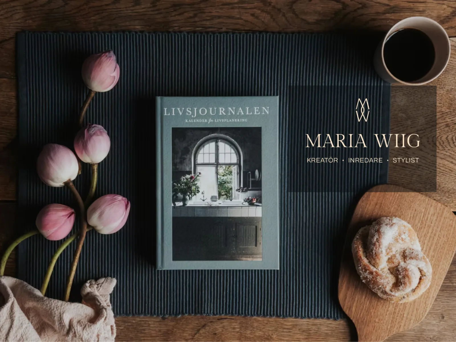 Logotypen med texten ”Kreatör · Inredare · Stylist” bredvid boken Livsjournalen på ett dukat bord.